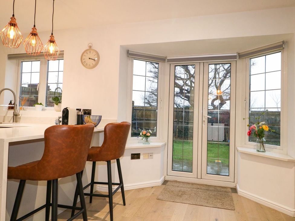 A kitchen with bar stools and a door leading to the outside at Number 5 