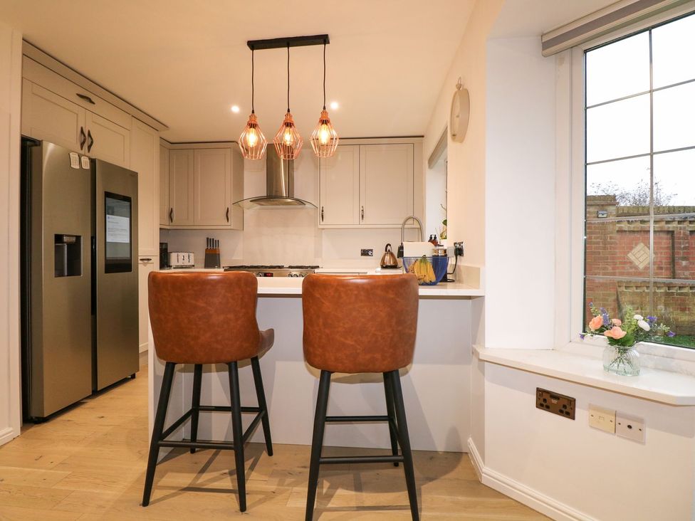A kitchen with bar stools and a refrigerator at Number 5 