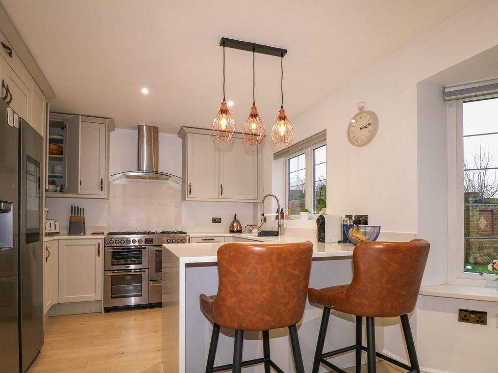 A kitchen with bar stools and appliances at Number 5