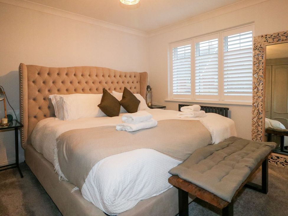 A bedroom with a bed, bedside table, and mirror at Number 5