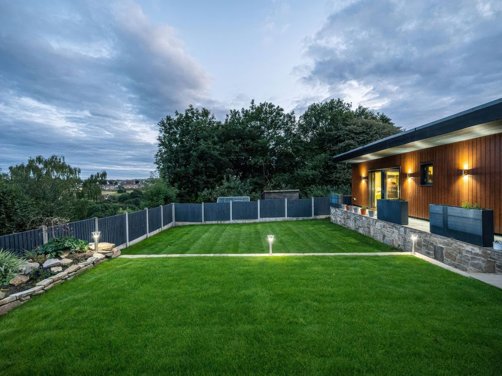 A garden with grass and stone wall at The Luxury Shed in Huddersfield