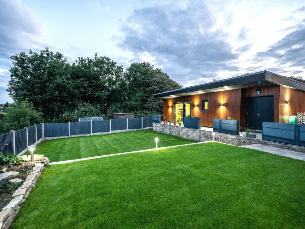 A garden with a house and fence at The Luxury Shed in Huddersfield
