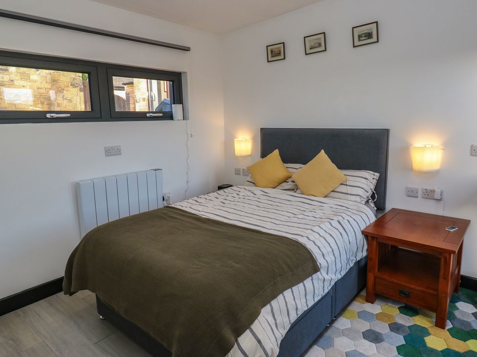A bedroom with a bed and bedside table at The Luxury Shed in Huddersfield