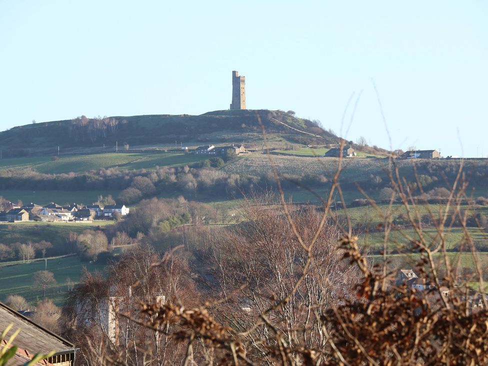 A view of a tower on a hill with fields and houses in the foreground at The Luxury Shed in Huddersfield