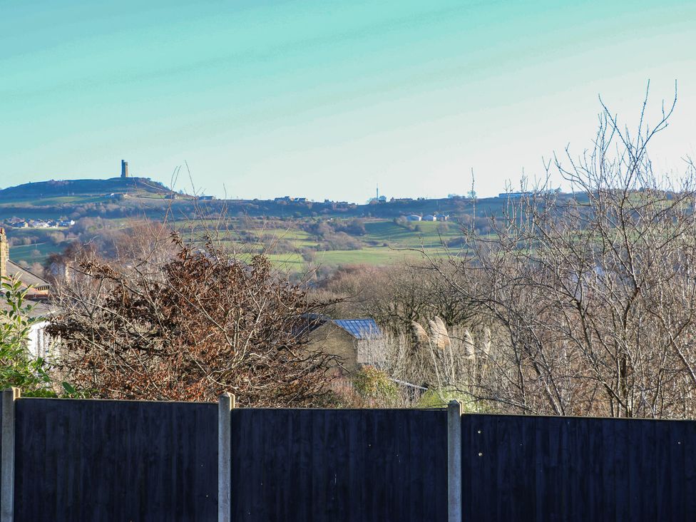 A view of a hill with a tower and trees from behind a fence at The Luxury Shed in Huddersfield