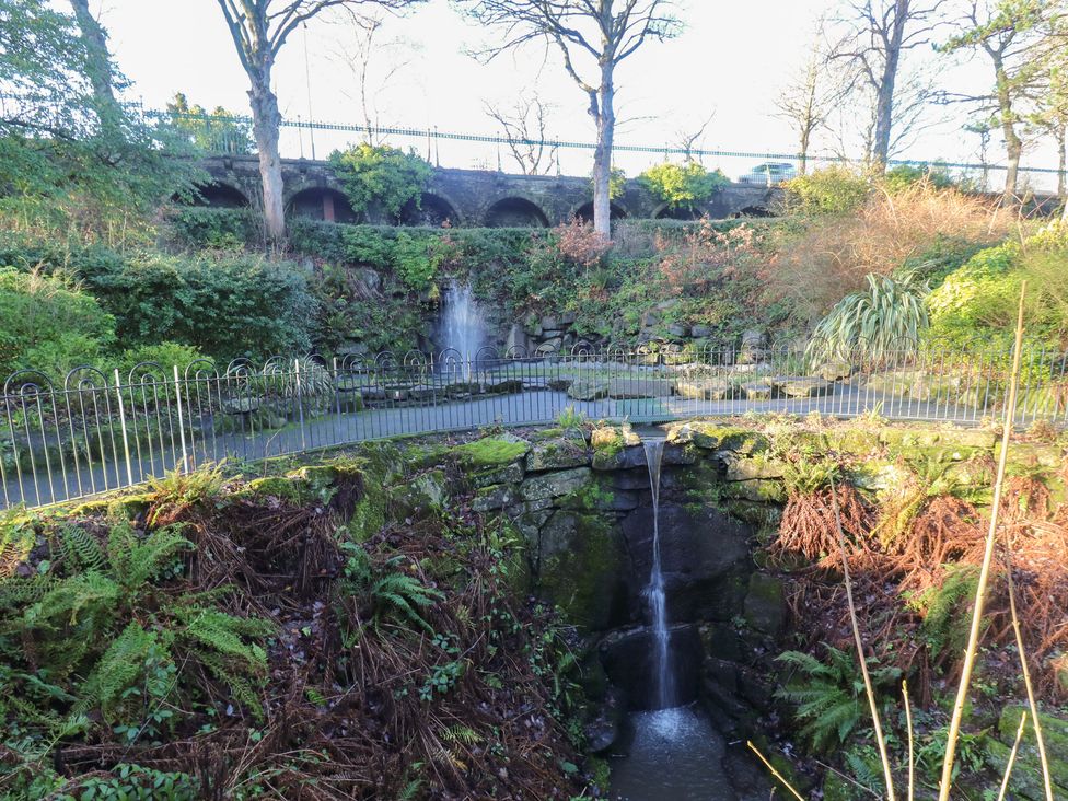 A waterfall and stone structure surrounded by trees at The Luxury Shed in Huddersfield