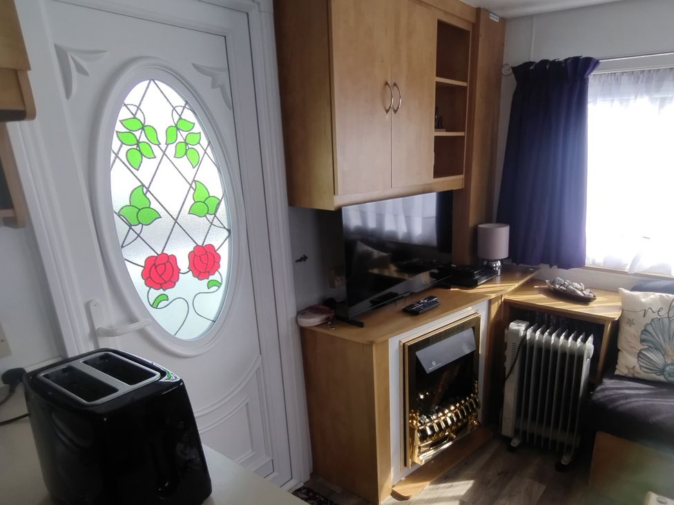 A living room with a television and a door at Whispering Meadows - 104 Great Yarmouth