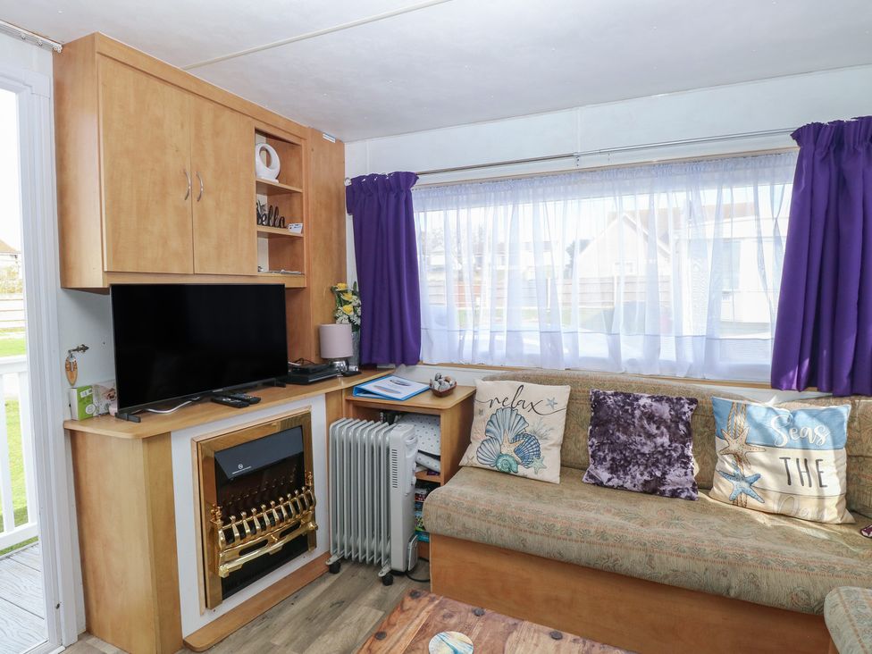 A living room with a television and a sofa at Whispering Meadows - 104 Hemsby
