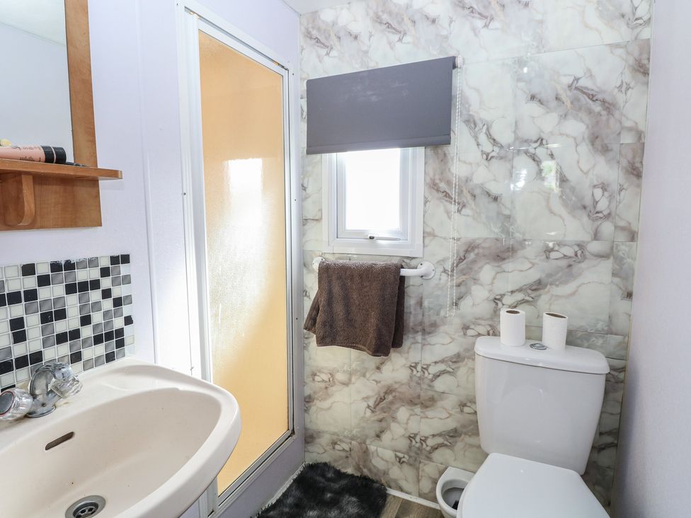 A bathroom with a sink, toilet, and shower at Whispering Meadows - 104 in Hemsby