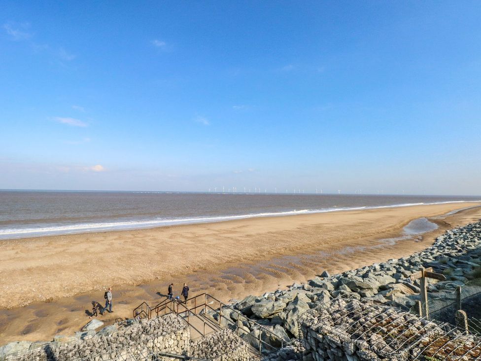 People walking on a beach with ocean and wind turbines at Whispering Meadows - 104 Hemsby