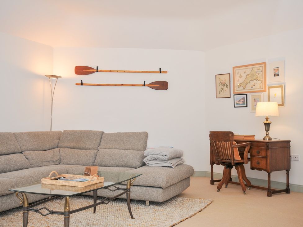 A living room with a sofa, lamp, desk, and pictures at Cribba in Port Isaac