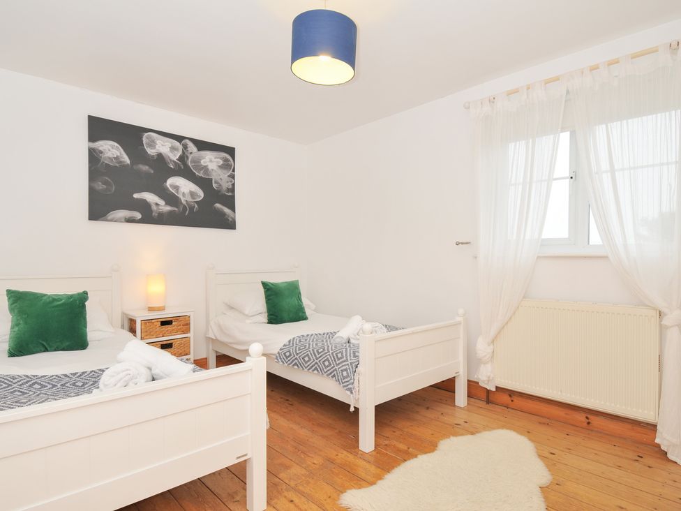 A bedroom with two beds and a nightstand at Cribba in Port Isaac