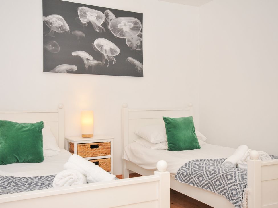 A bedroom with two beds and a lamp at Cribba in Port Isaac