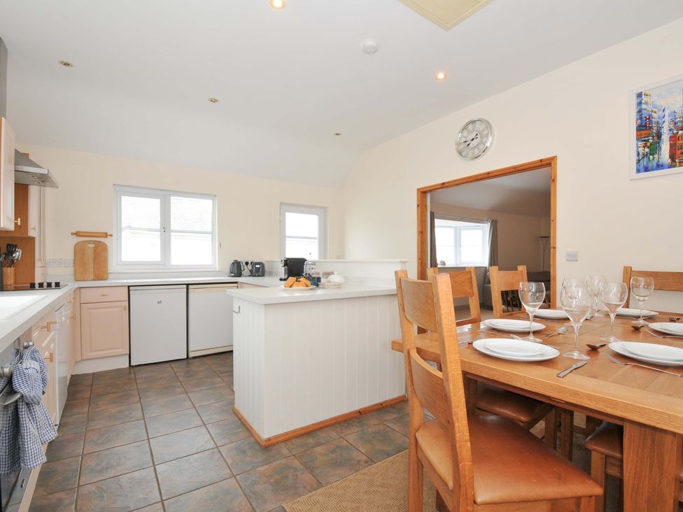 A kitchen with a countertop, cabinets, and dining area at Cribba in Port Isaac