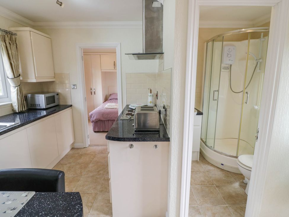 A kitchen equipped with appliances and an adjacent bathroom at Cabin In The Woods Silverstone
