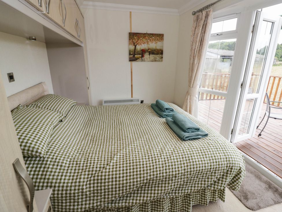 A bedroom with a bed and towels at Cabin In The Woods in Silverstone