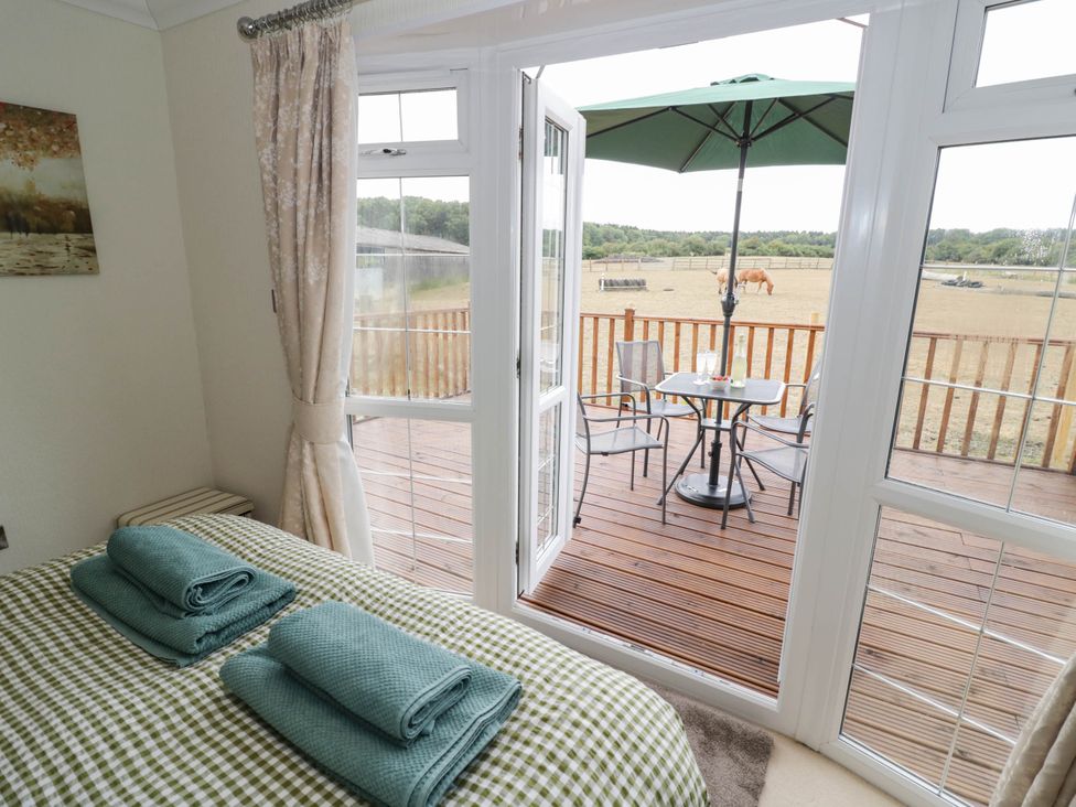 A bedroom with a bed and opening to a deck at Cabin In The Woods Silverstone