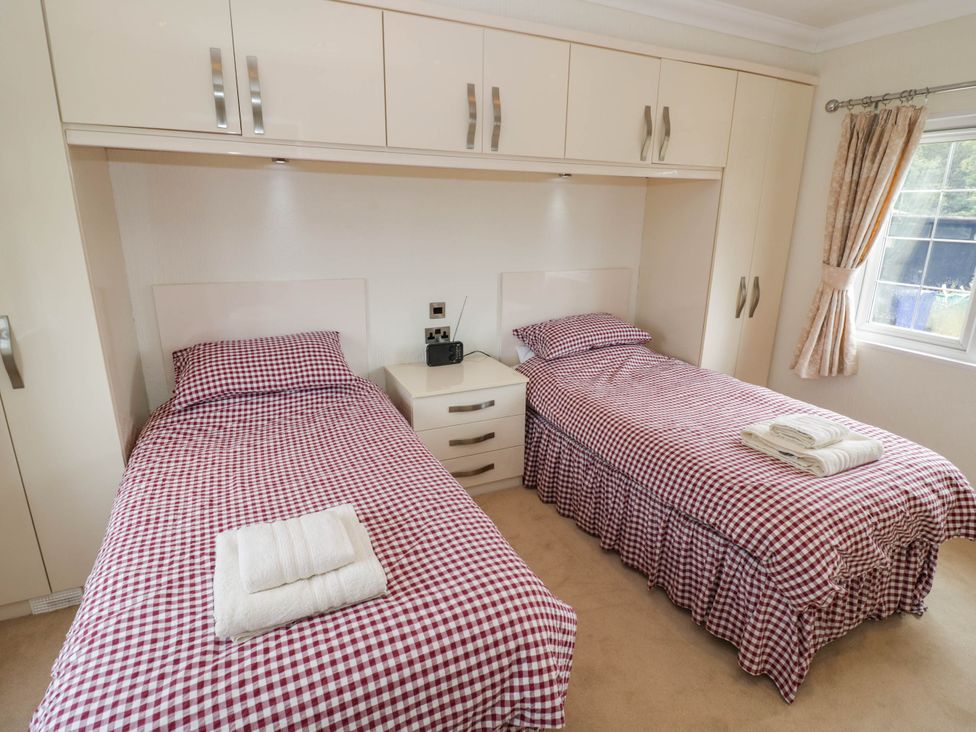 A bedroom with two single beds and a bedside table at Cabin In The Woods in Silverstone
