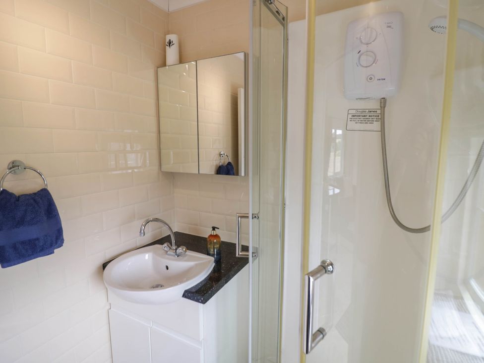 A bathroom with a sink, shower, and mirror at Cabin In The Woods in Silverstone