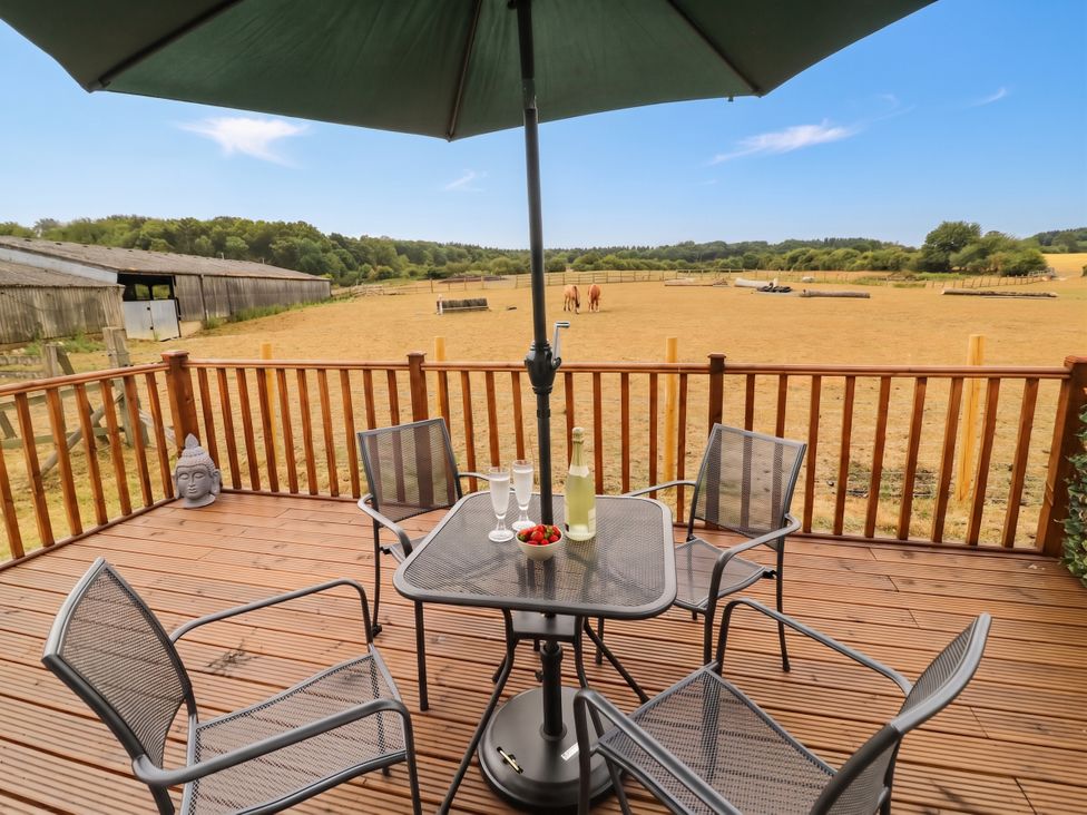A deck with a table and chairs at Cabin In The Woods Silverstone
