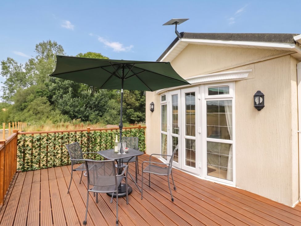 A deck with chairs and an umbrella at Cabin In The Woods Silverstone