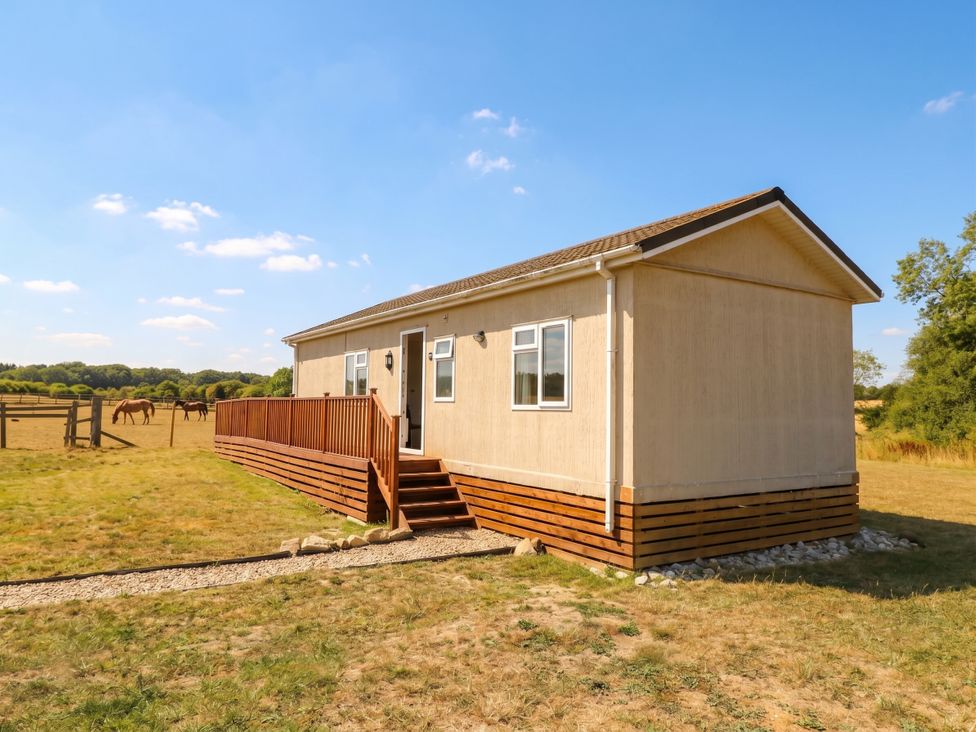 A mobile home with wooden deck in an outdoor area at Cabin In The Woods Silverstone