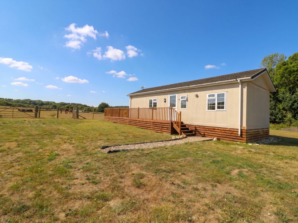A mobile home with a wooden deck at Cabin In The Woods Silverstone