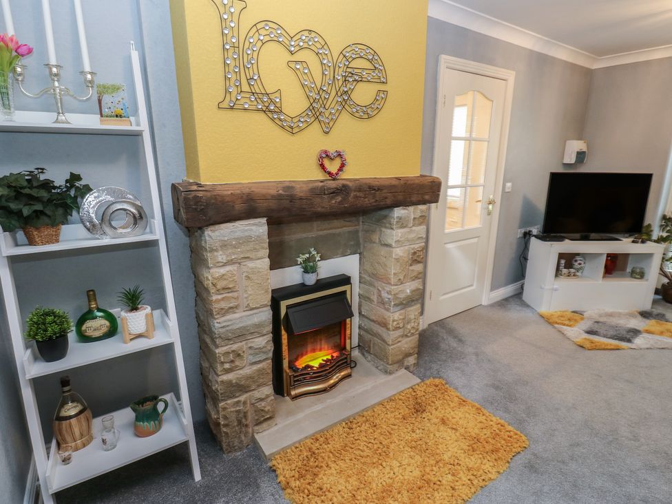 A living room with a fireplace and TV at The Annex at Ryefield Lodge