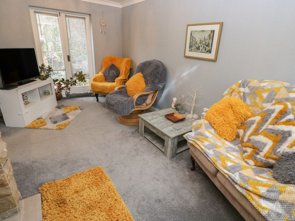 A living room with a television and two seating areas at The Annex at Ryefield Lodge 