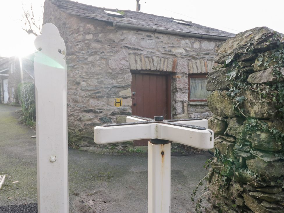 A stone building with a door beside a signpost in Grange-over-Sands