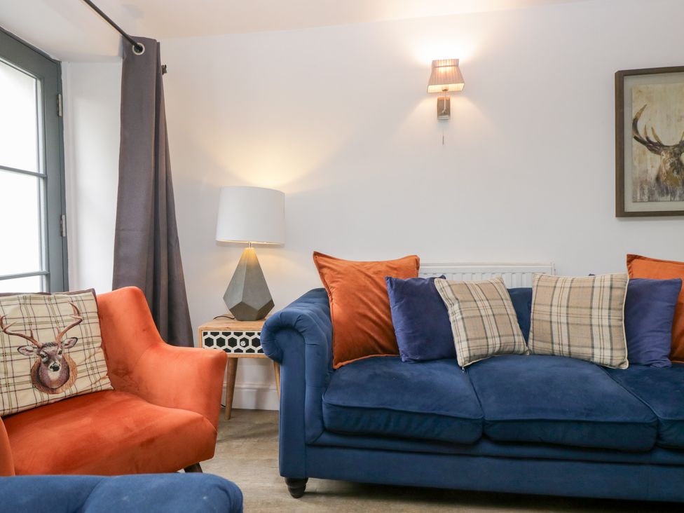 A living room with a blue sofa and orange armchair at No.2 The Flags, Grange-over-Sands