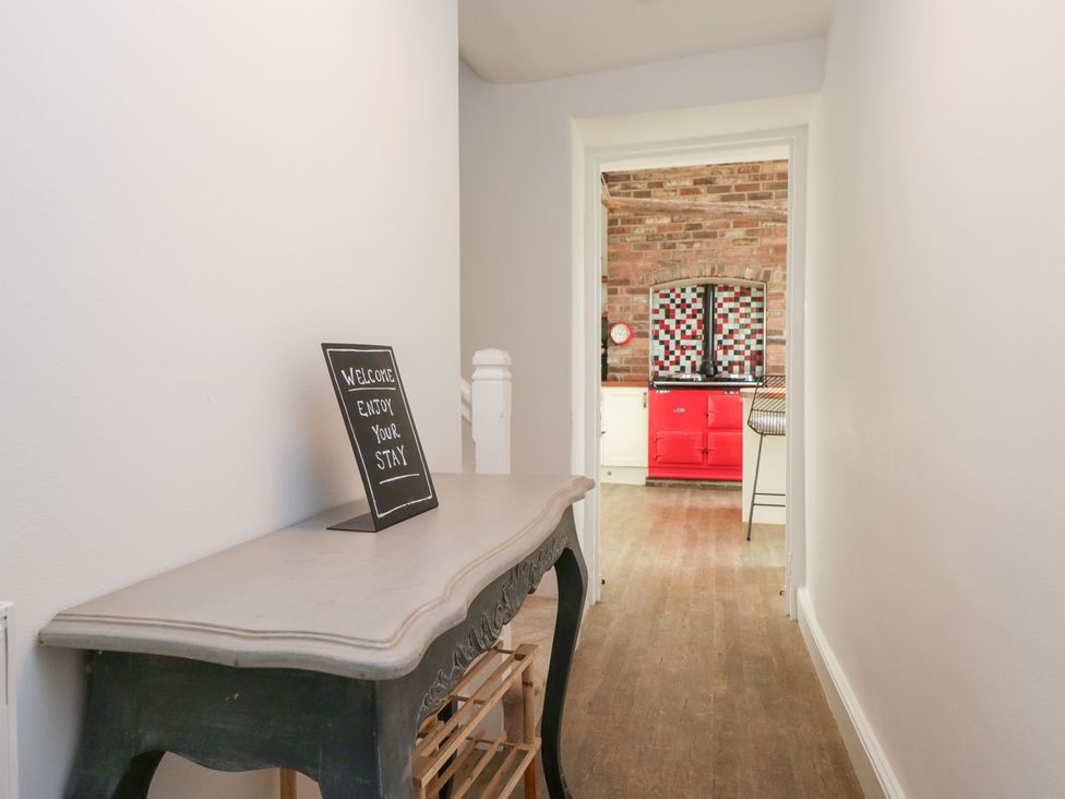 A hallway with a table and welcome sign leading to a kitchen at No.2 The Flags, Grange-over-Sands