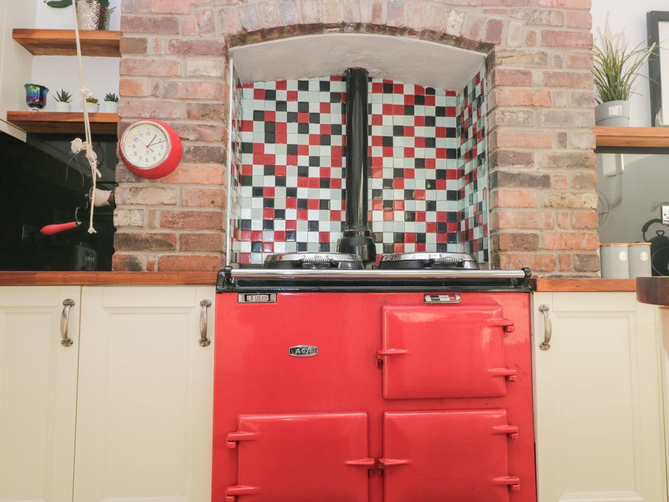 A kitchen with a red stove and tiled backsplash at No.2 The Flags, Grange-over-Sands
