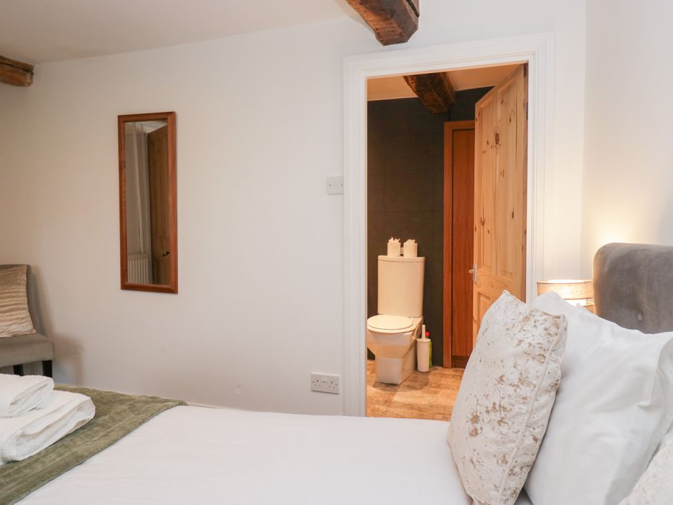 A bedroom with a bed and a bathroom door at No.2 The Flags in Grange-over-Sands