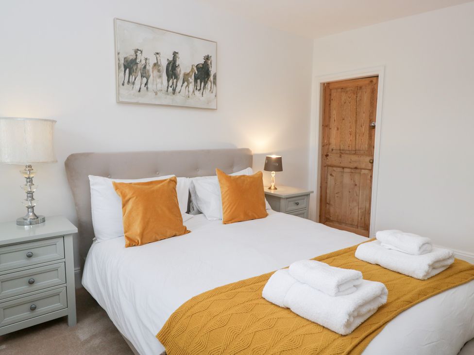 A bedroom with a bed, pillows, and a door at No.2 The Flags, Grange-over-Sands