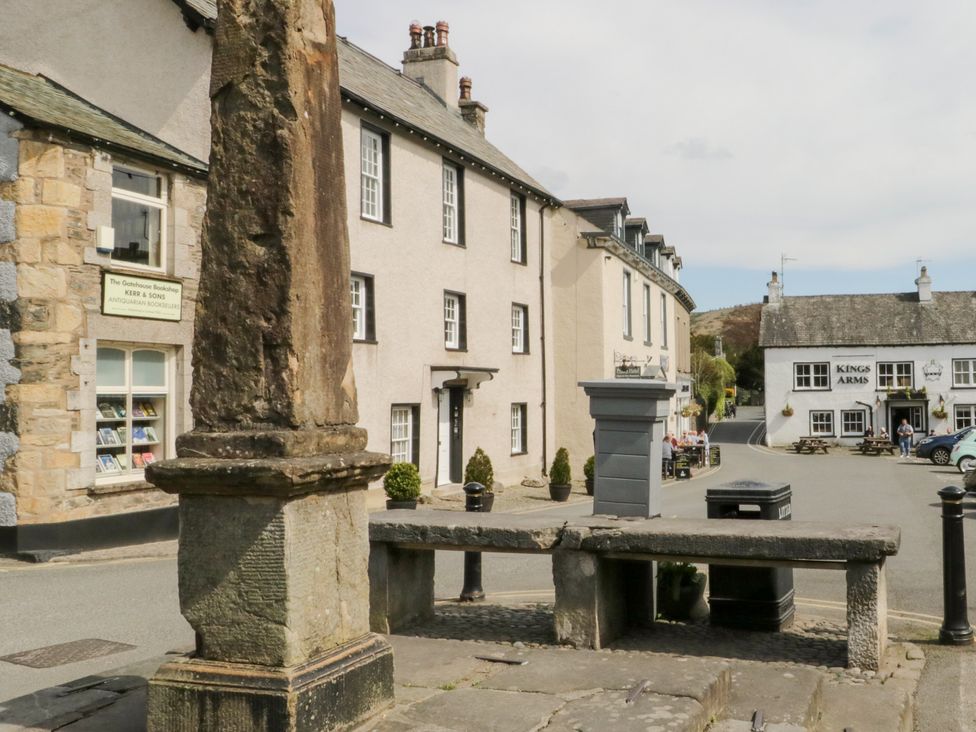 An outdoor scene featuring a street with buildings and a bench at No.2 The Flags, Grange-over-Sands