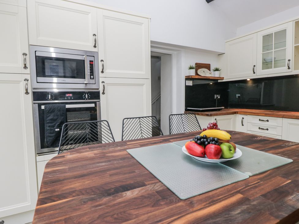 A kitchen with cabinets and appliances, featuring a dining table with fruits at No.2 The Flags in Cartmel