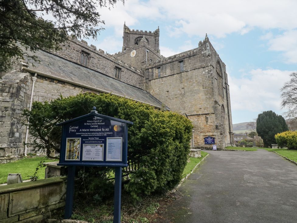 An exterior view of a church with a signboard and pathway at No.2 The Flags in Cartmel
