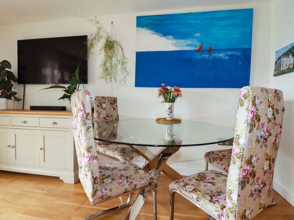 A dining room with a glass table and television at 2 Morweth View, Torpoint