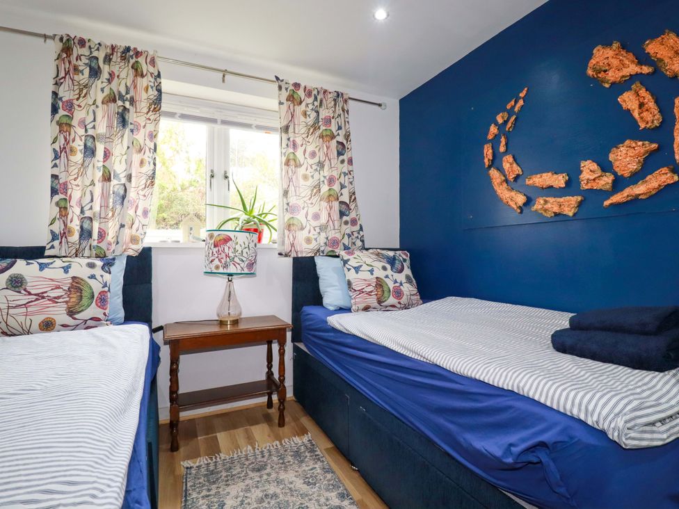 A bedroom with two beds and a side table at 2 Morweth View in Torpoint