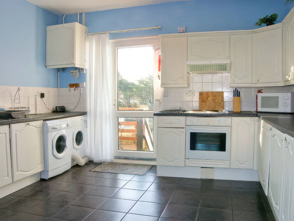 A kitchen with appliances and cabinets at Morlais in Rhosneigr
