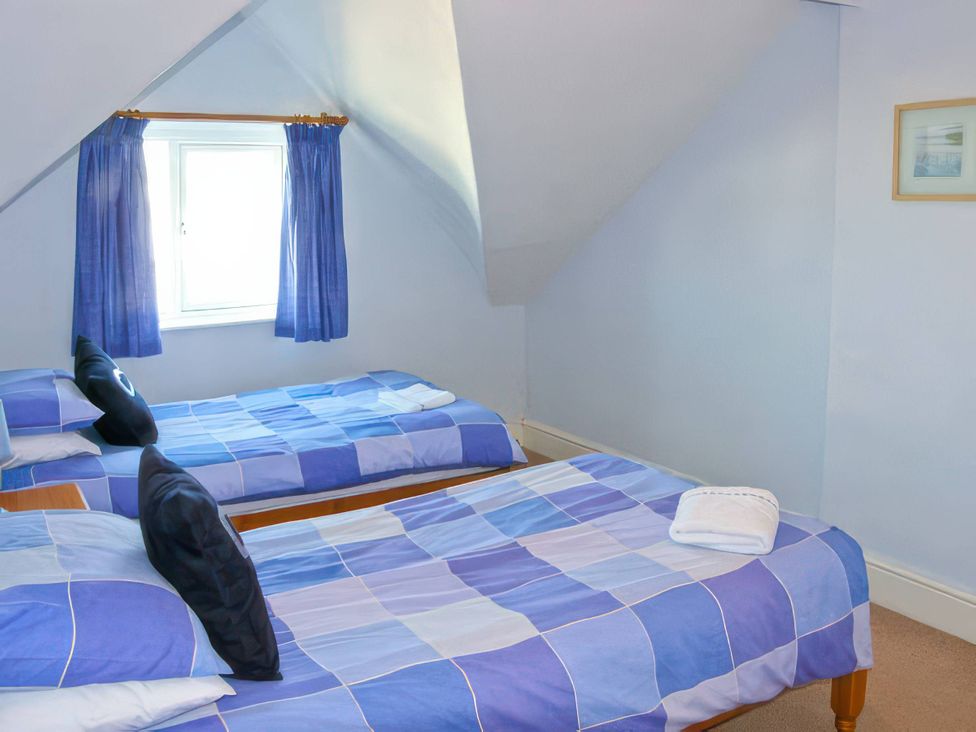 A bedroom with two single beds and a window at Morlais Rhosneigr