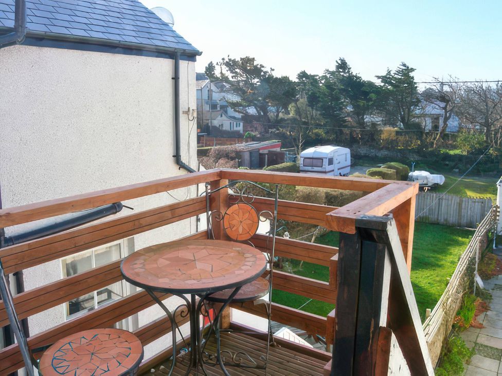 A balcony with a table and chairs overlooking a garden at Morlais in Rhosneigr