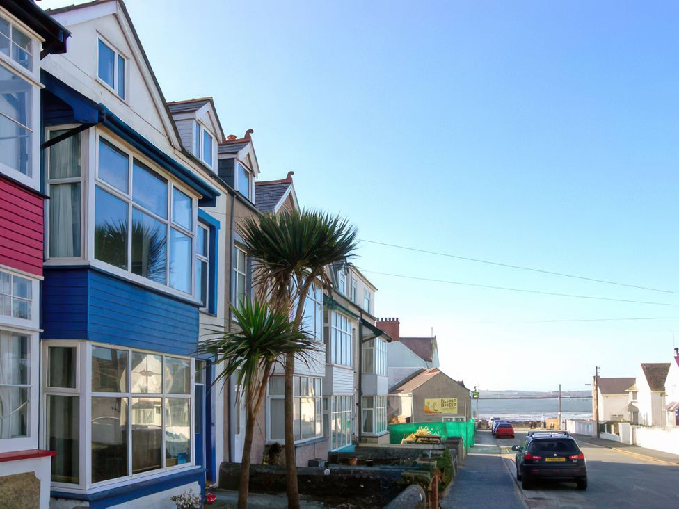 A street view of houses with palm trees and a car at Morlais in Rhosneigr