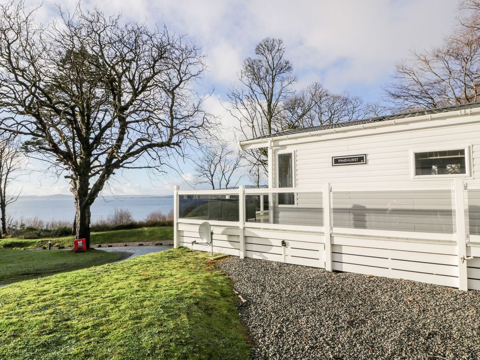 A house with a gravel area and a tree near a lake at Serenity Lodge Wemyss Bay