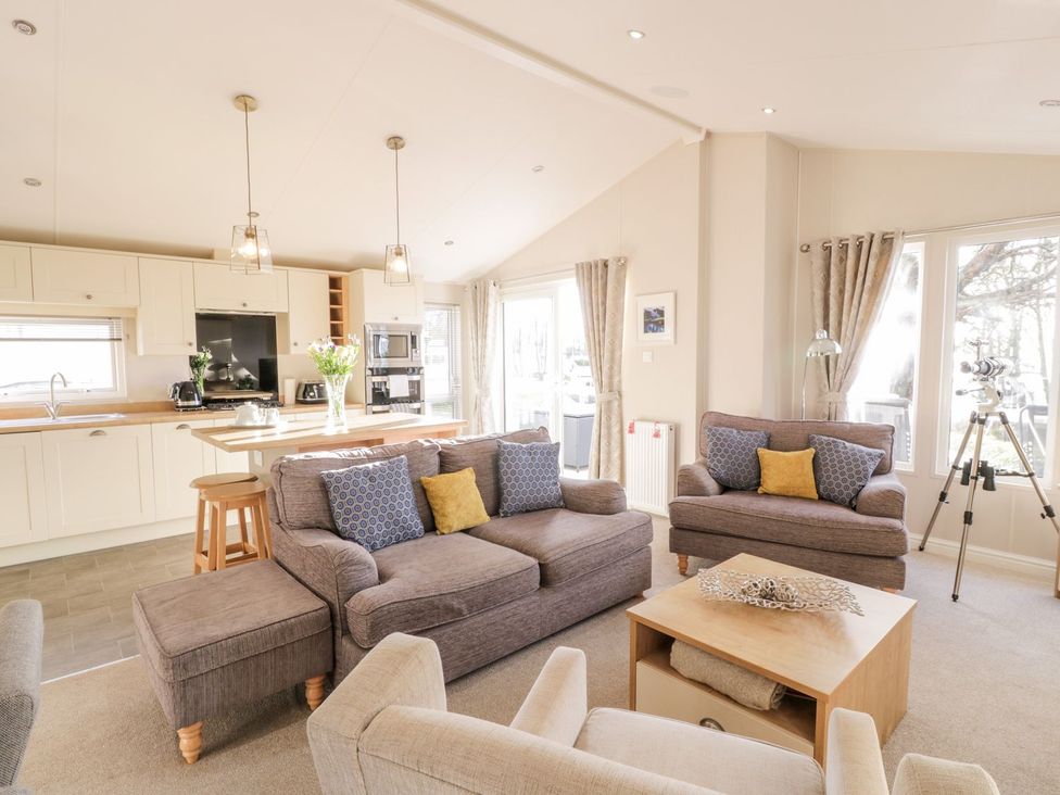 A living room with sofas and kitchen units at Serenity Lodge in Wemyss Bay