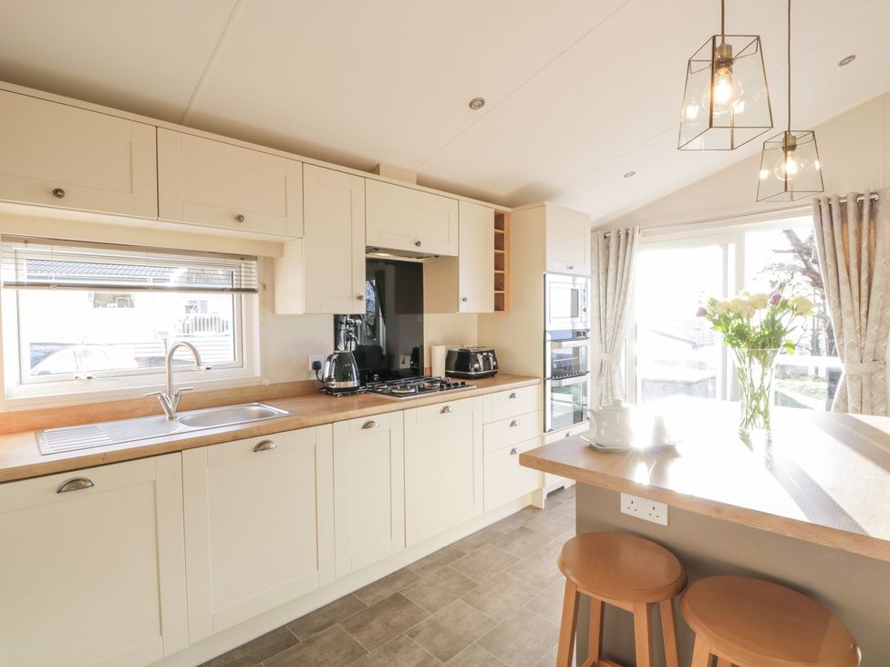 A kitchen with cabinets and appliances at Serenity Lodge in Wemyss Bay