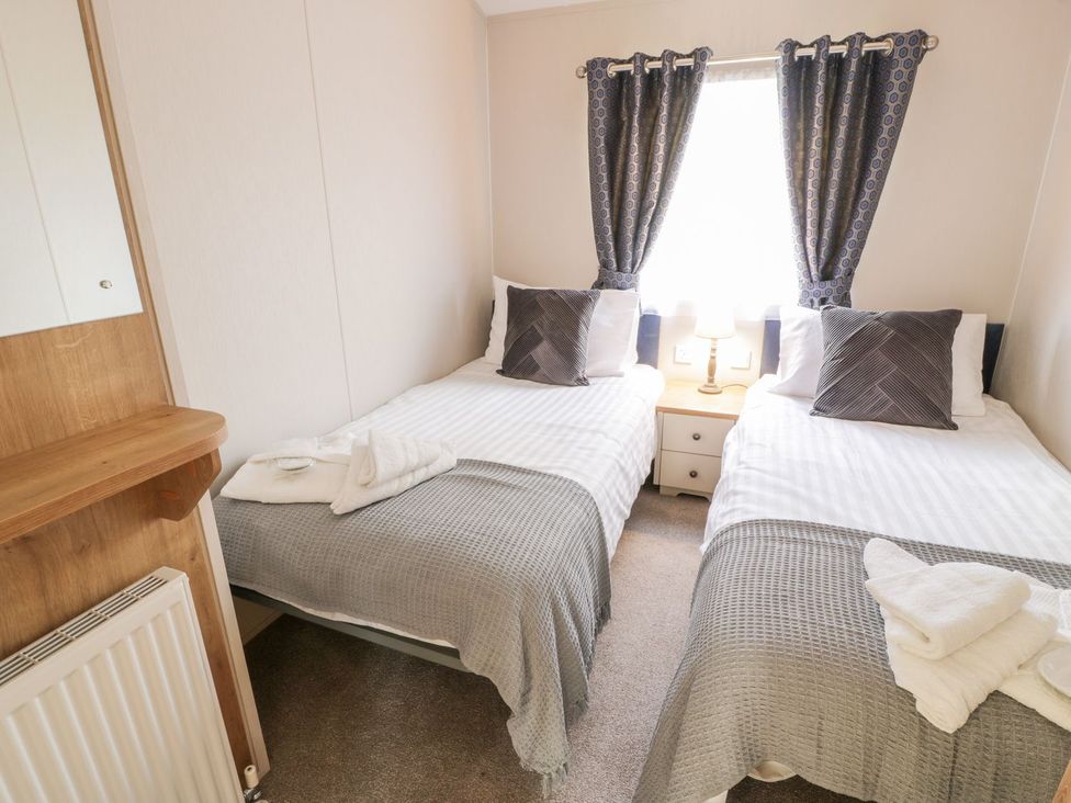 A bedroom with twin beds and a lamp at Serenity Lodge, Wemyss Bay