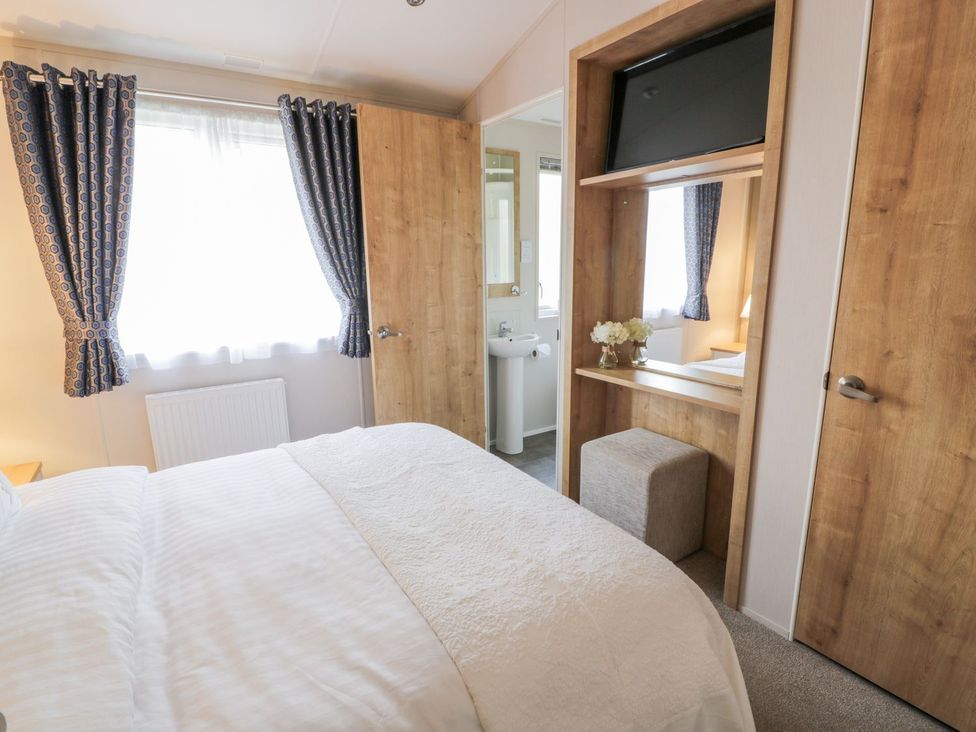 A bedroom with a bed and a TV at Serenity Lodge in Wemyss Bay
