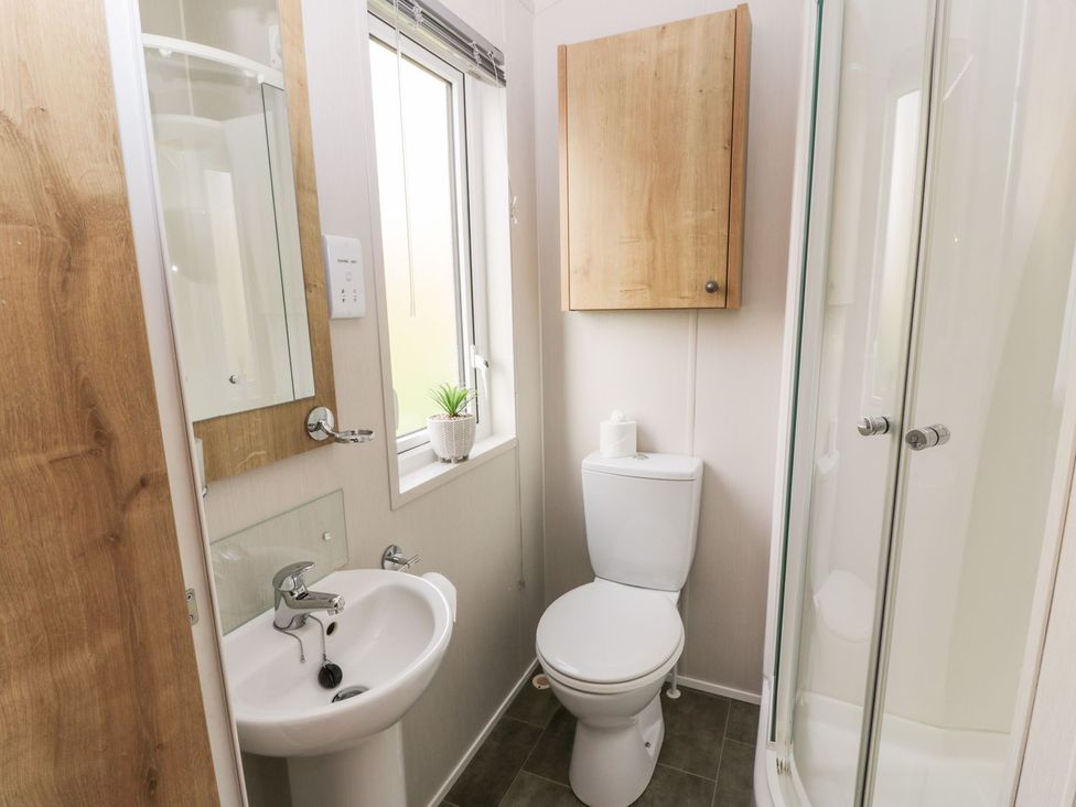 A bathroom with a sink, toilet, shower and window at Serenity Lodge in Wemyss Bay
